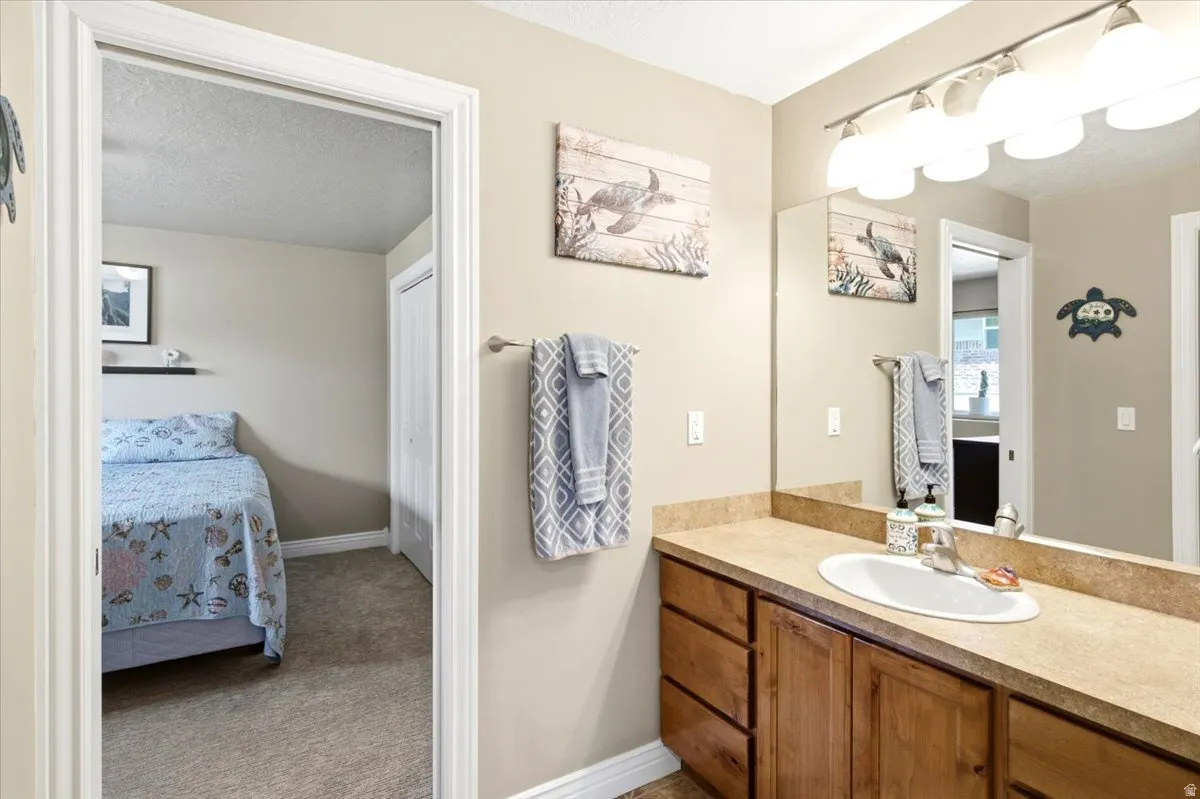 Bathroom vanity featuring a single basin sink, laminate countertop, and wood-finish cabinetry
