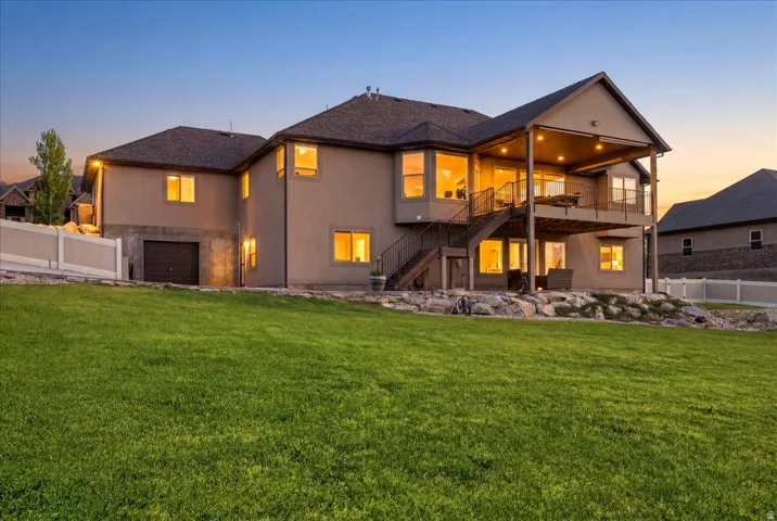 Stucco exterior residence with a multi-level deck, lower-level patio, and an integrated garage
