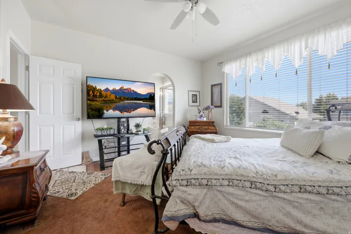 Carpeted interior space featuring a ceiling fan, a window with horizontal blinds, and a white six-panel interior door