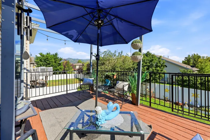 Expansive wooden deck featuring black metal railings and overhead string lighting