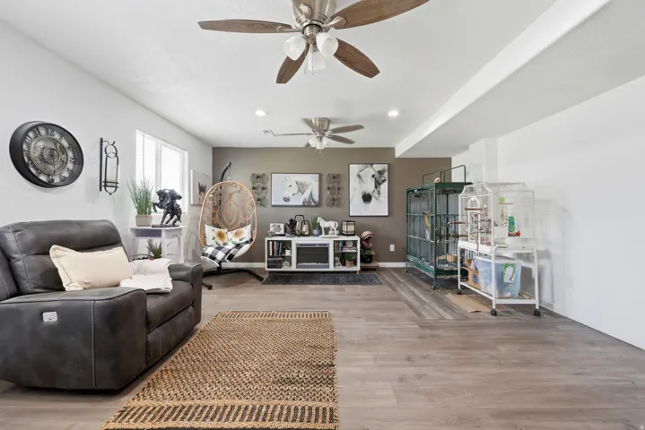 Spacious living area featuring wood-finish flooring, recessed lighting, and dual ceiling fans