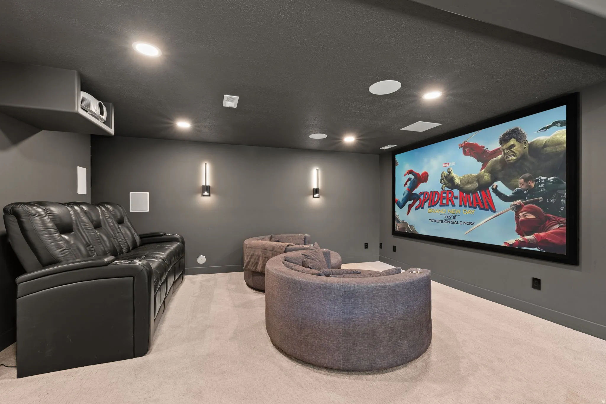 Dedicated home theater featuring a large projection screen, recessed lighting, and wall-mounted sconces
