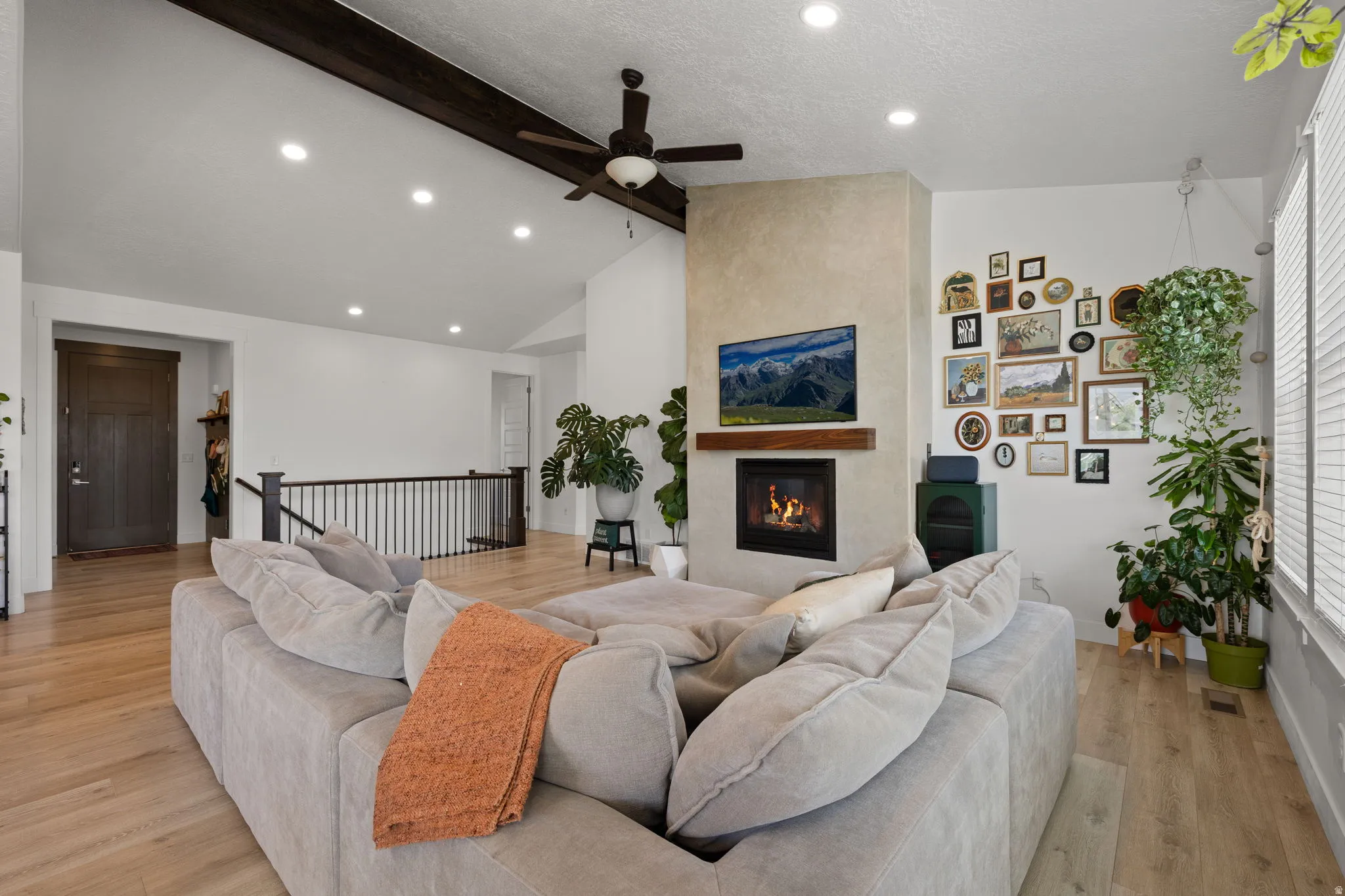 Spacious living area featuring a vaulted ceiling with exposed beams, recessed lighting, and a ceiling fan