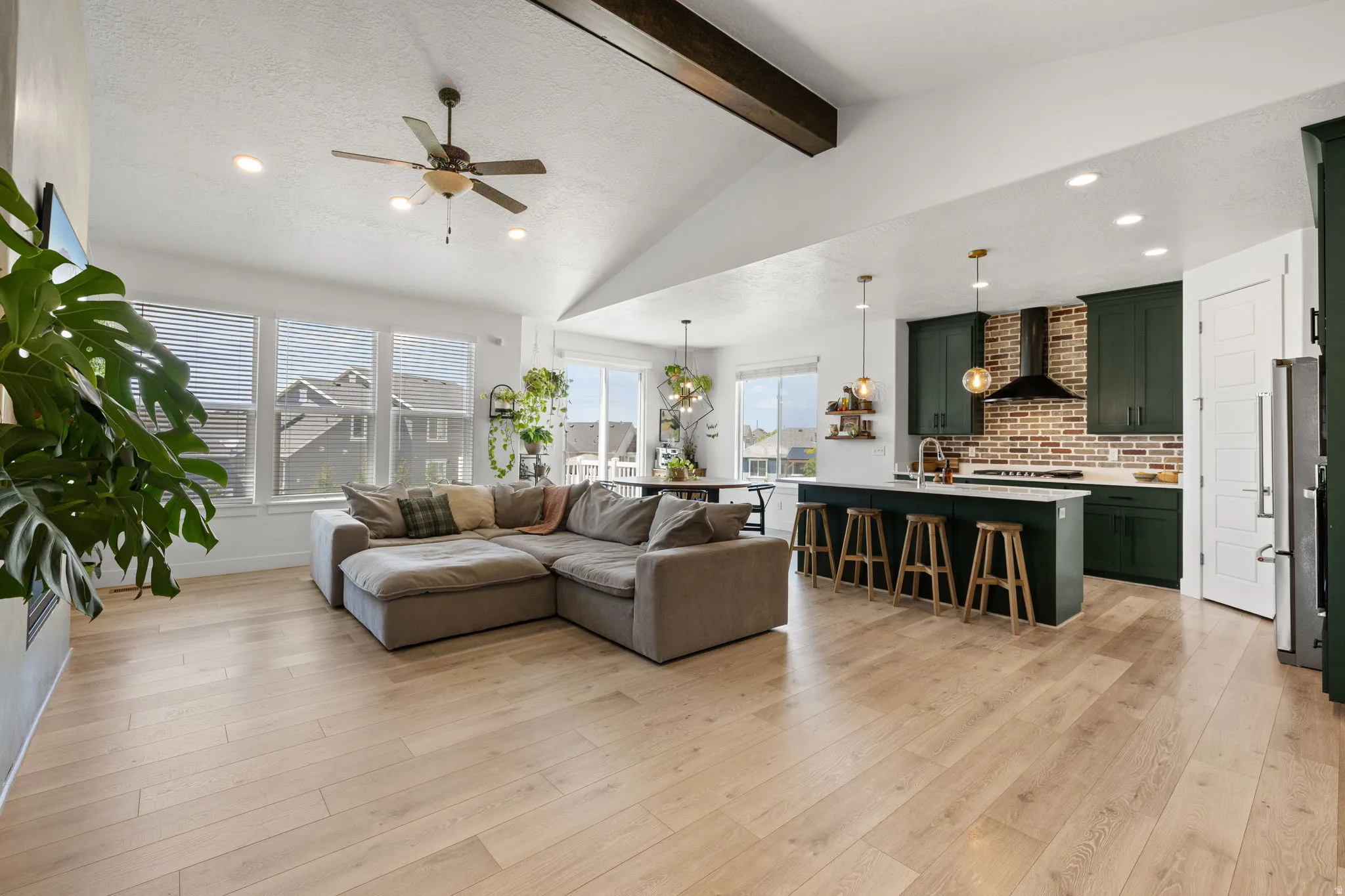 Open-concept living space featuring wood-finish flooring, vaulted ceilings with exposed beam, and recessed lighting