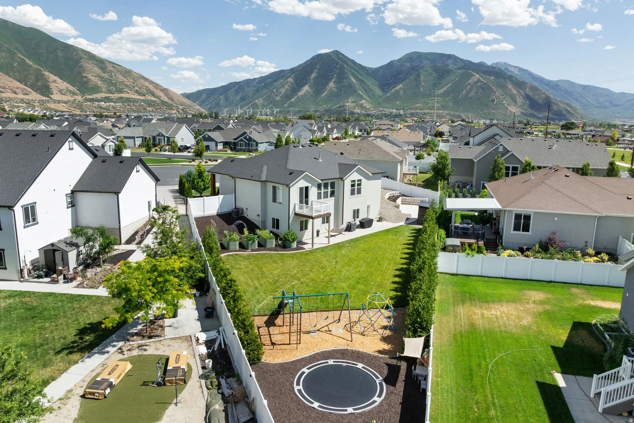 Expansive backyard featuring a manicured lawn, established trees, and mountain scenery