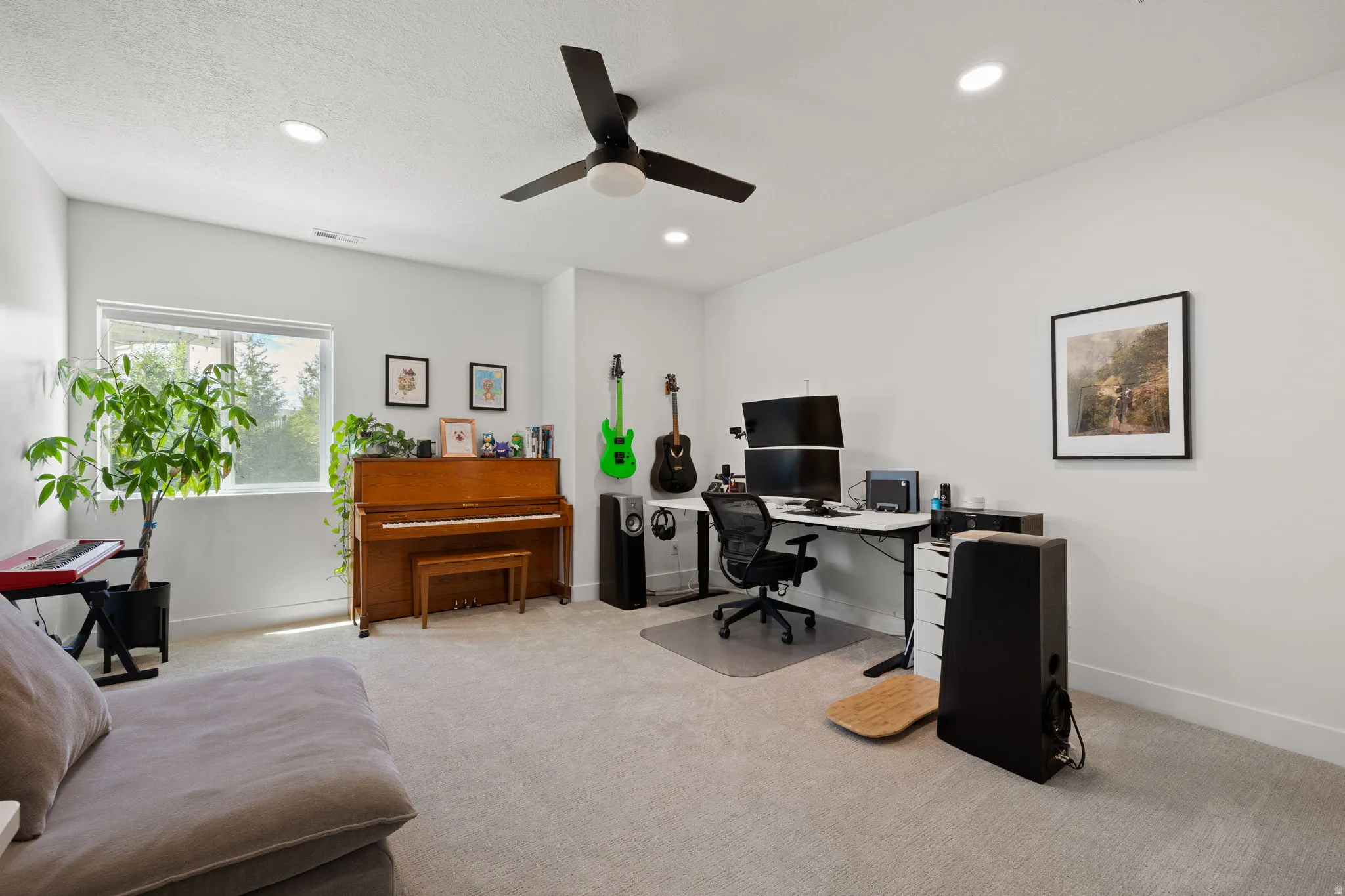 Bright interior space featuring light-toned carpeting, white walls, recessed lighting, and a ceiling fan