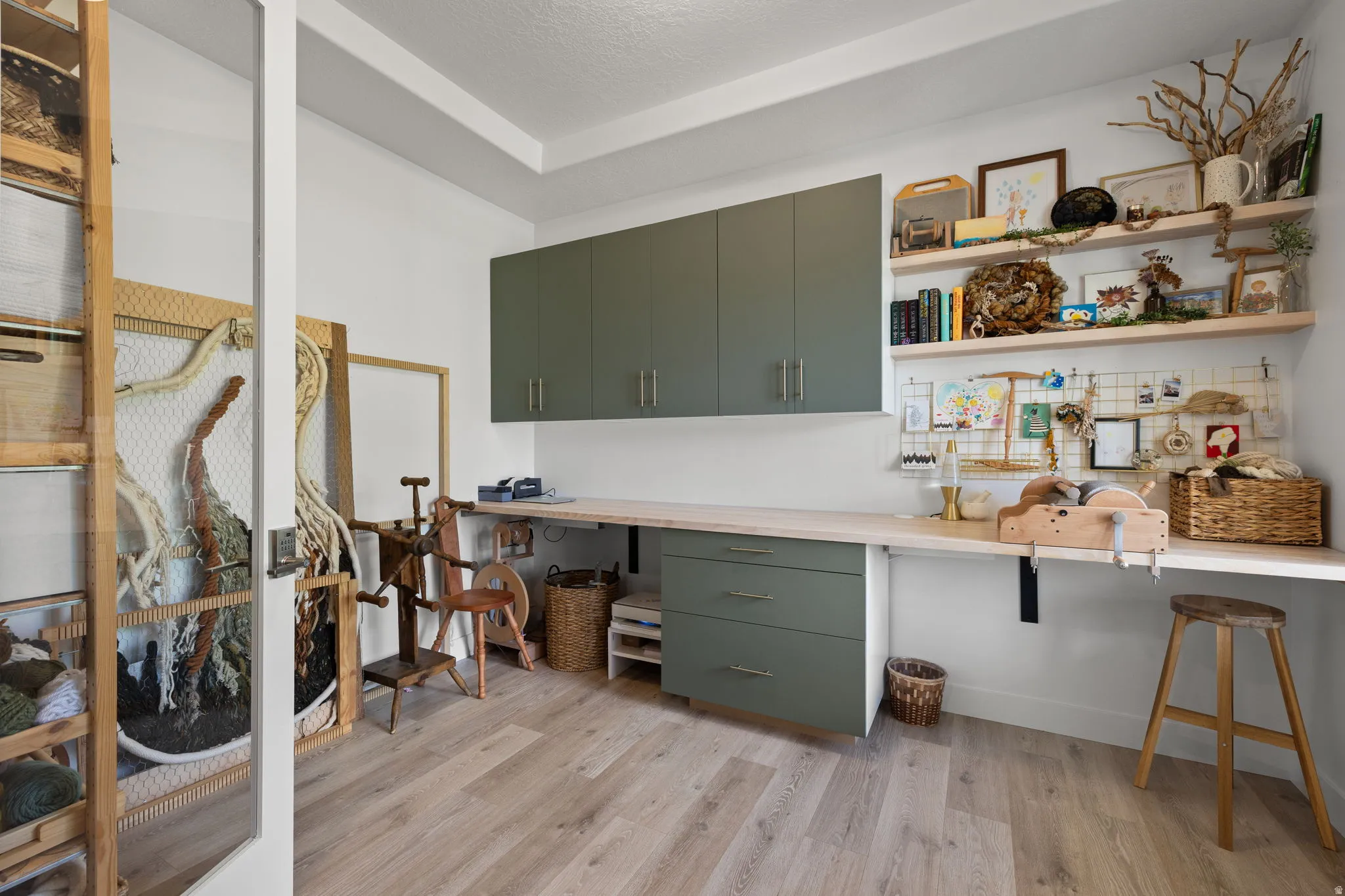 Dedicated workspace featuring wood-finish flooring, built-in cabinetry, an expansive desktop, wall-mounted shelving, and overhead lighting