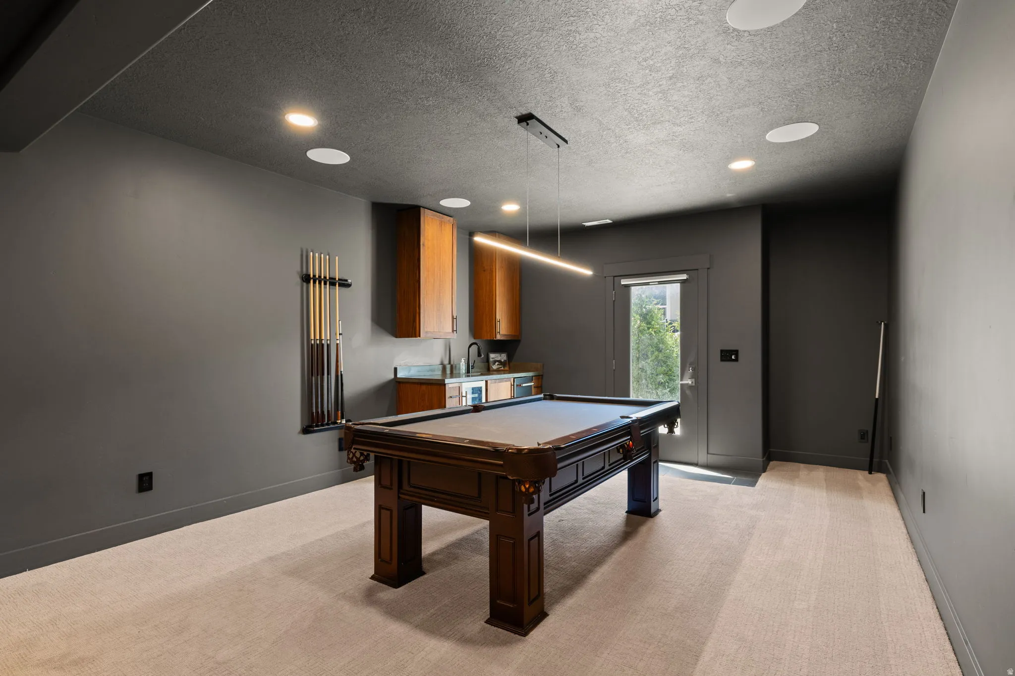 Recreation room featuring recessed lighting, a built-in wet bar with wood cabinetry, and light-toned carpeting