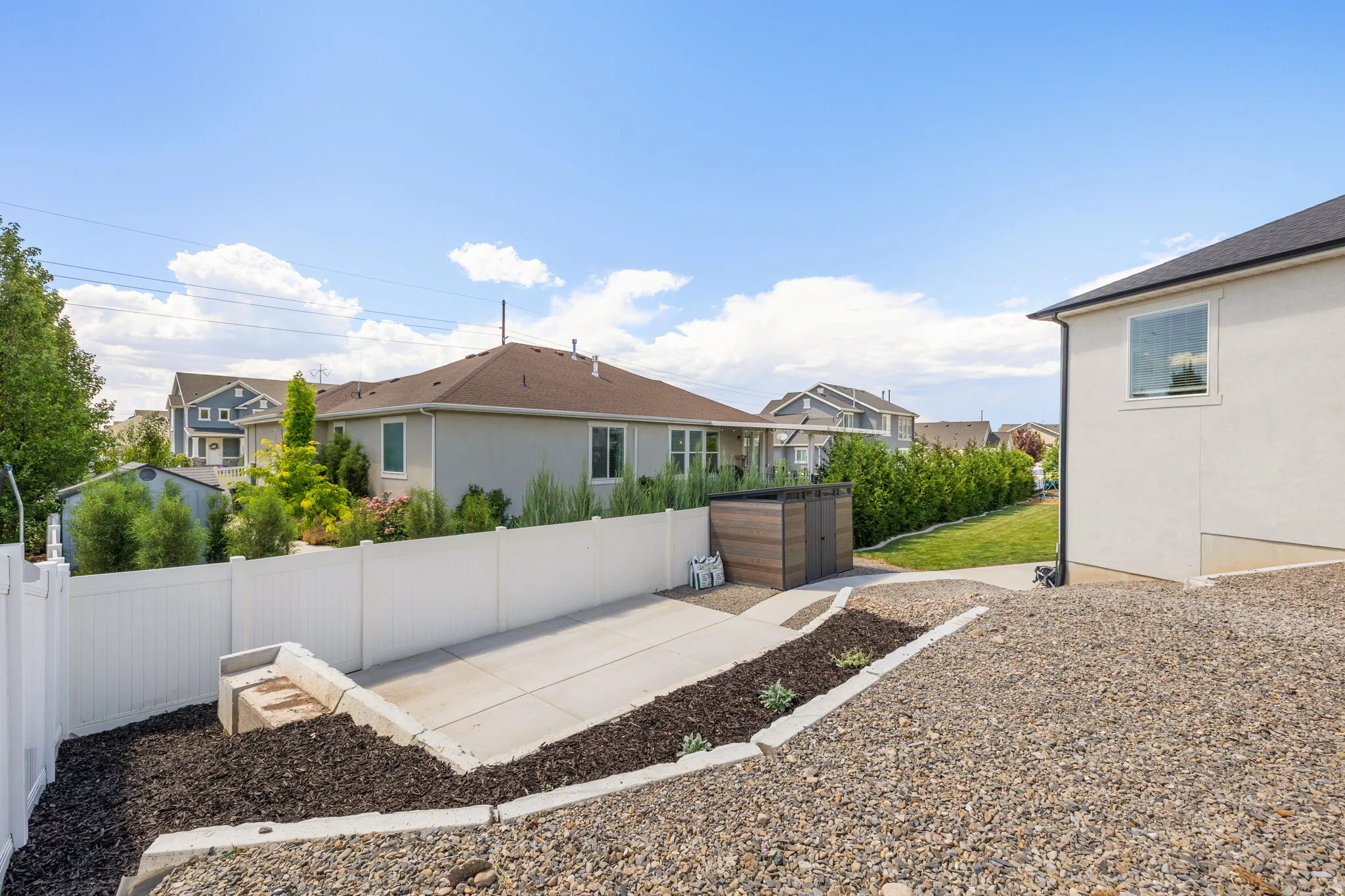 Private outdoor space featuring a white privacy fence, concrete patio, and a dedicated gravel area