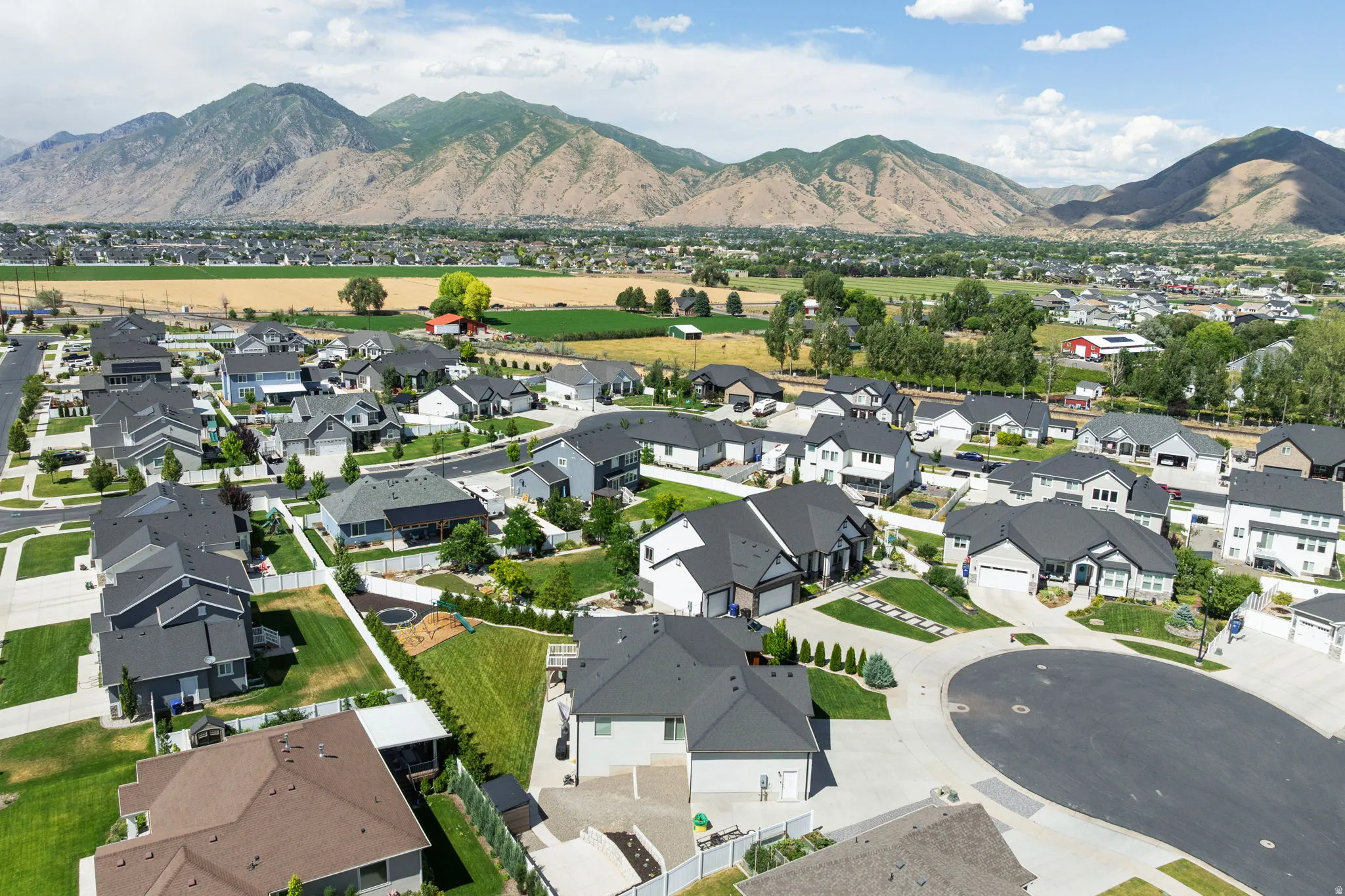 Residential neighborhood with diverse home styles, featuring manicured lawns, mature landscaping, and mountain scenery