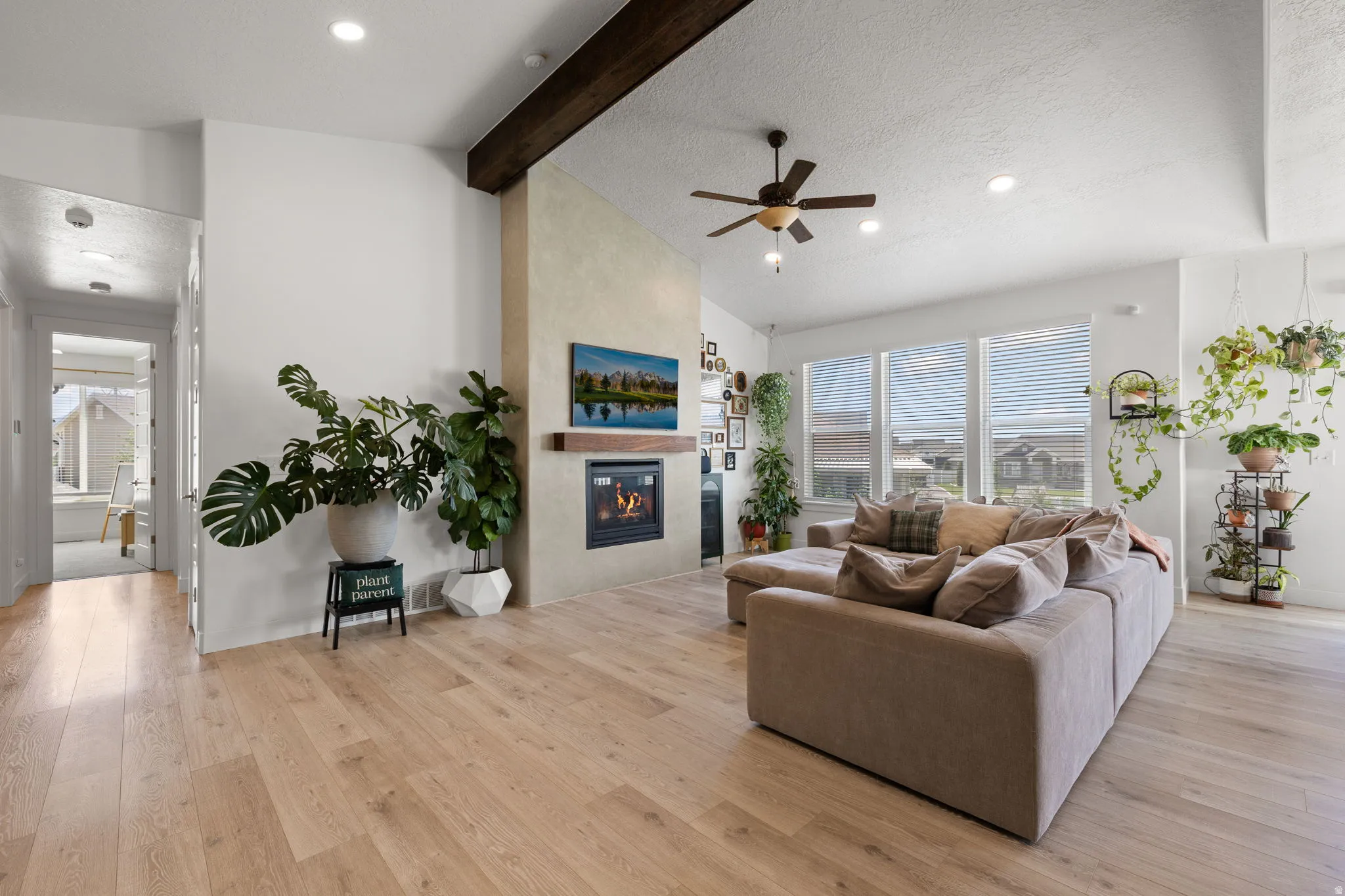Living area featuring wood-finish flooring, a contemporary fireplace with a wooden mantel, and a ceiling fan