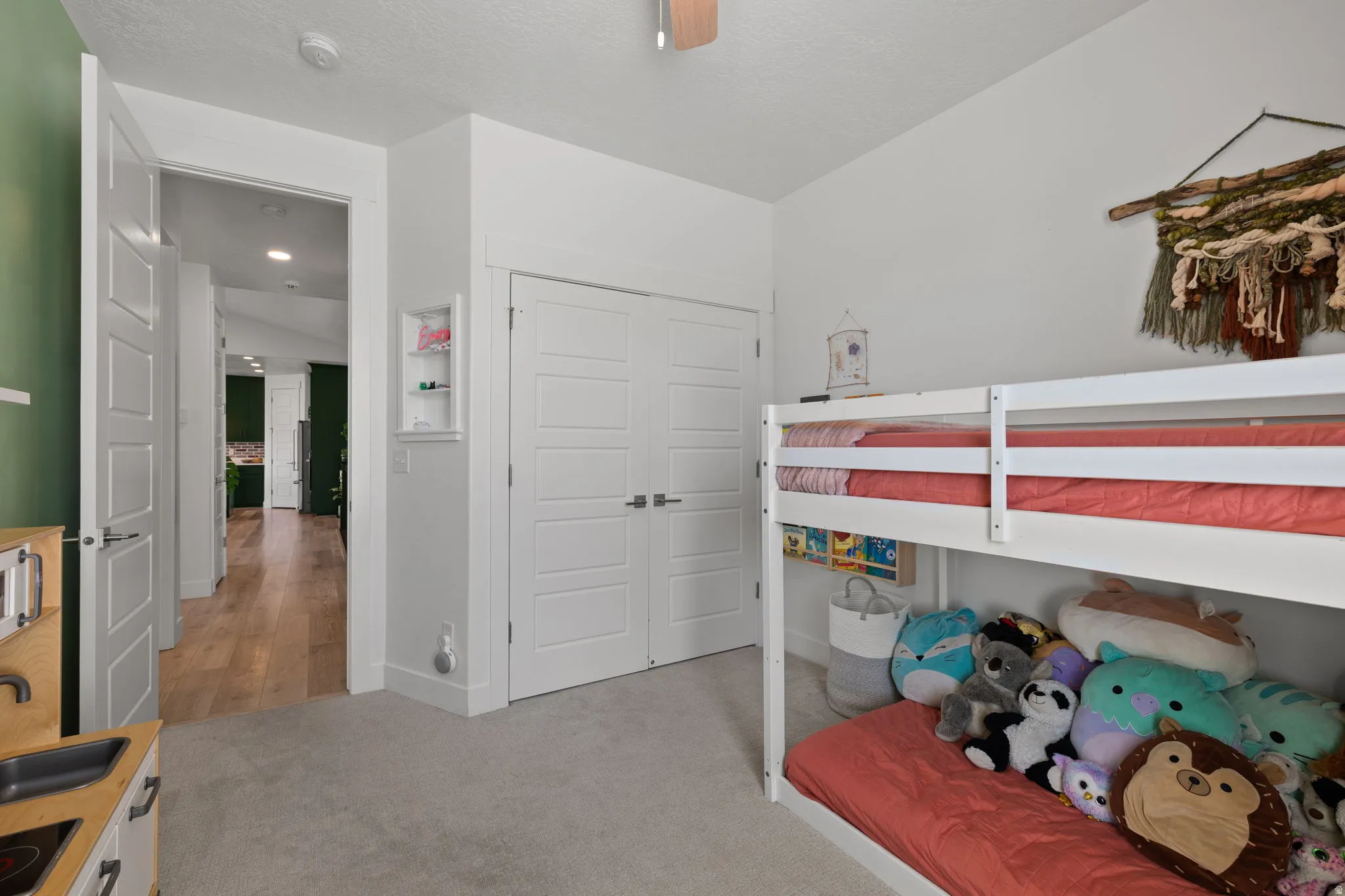 Carpeted room with a hallway entry, featuring a recessed wall shelf and a double-door closet
