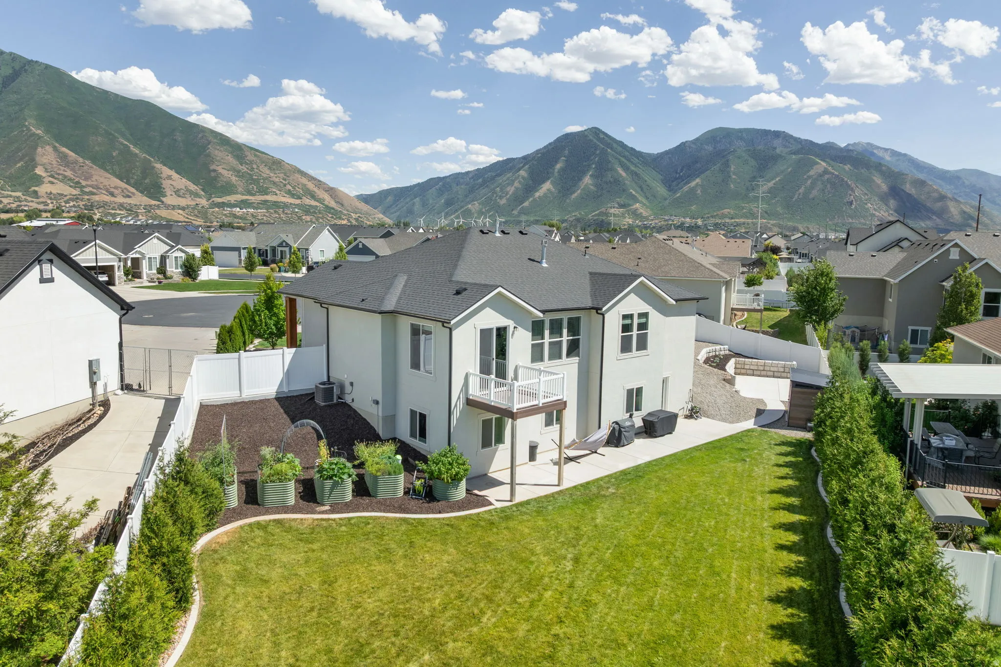 Expansive backyard featuring a manicured lawn, tiered landscaping, and mature trees
