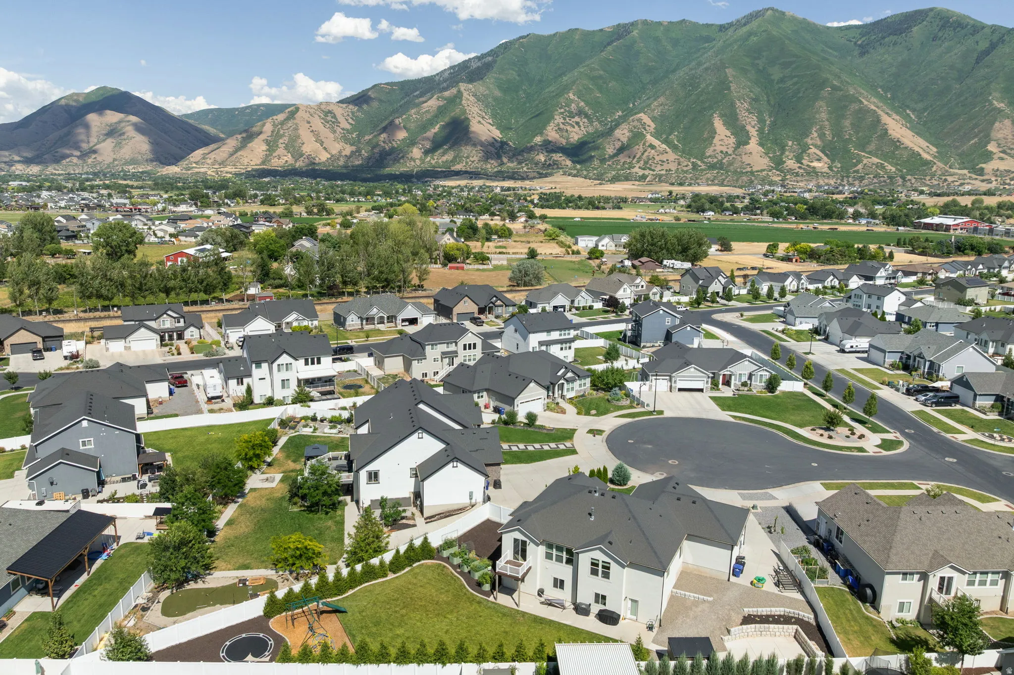 Residential community with mountain backdrop, featuring single-family homes, manicured green spaces, and paved streets