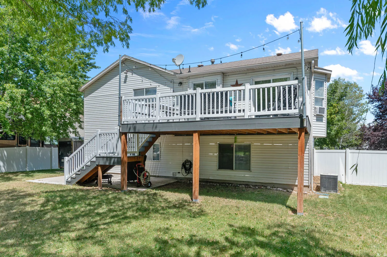 Rear exterior with a multi-level deck featuring white railings and string lights