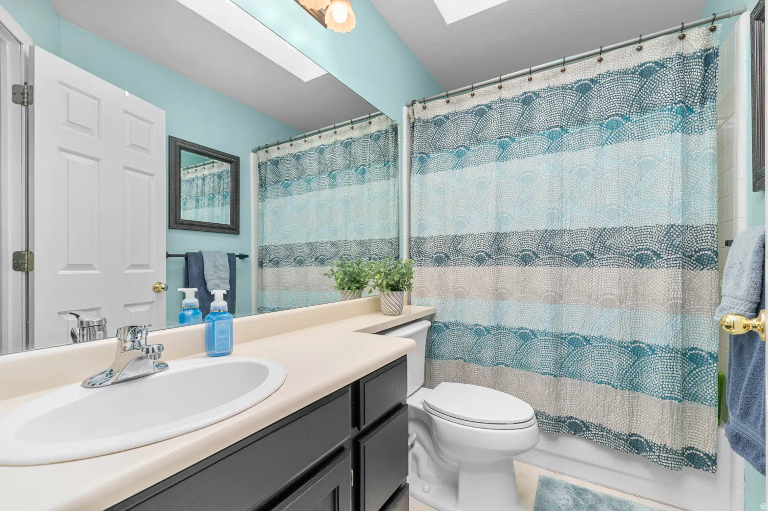 Bathroom featuring a built-in vanity with a cream-toned countertop, an undermount sink, and dark wood-finish cabinetry