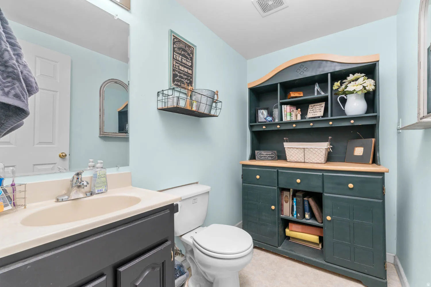 Bathroom featuring a vanity with an integrated sink, a large wall mirror, and a toilet