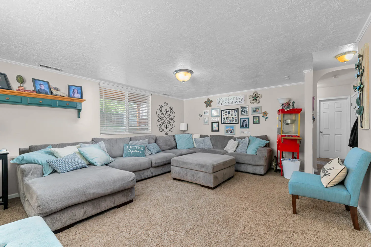 Carpeted living area featuring a large window with blinds, recessed ceiling lighting, and an arched entry