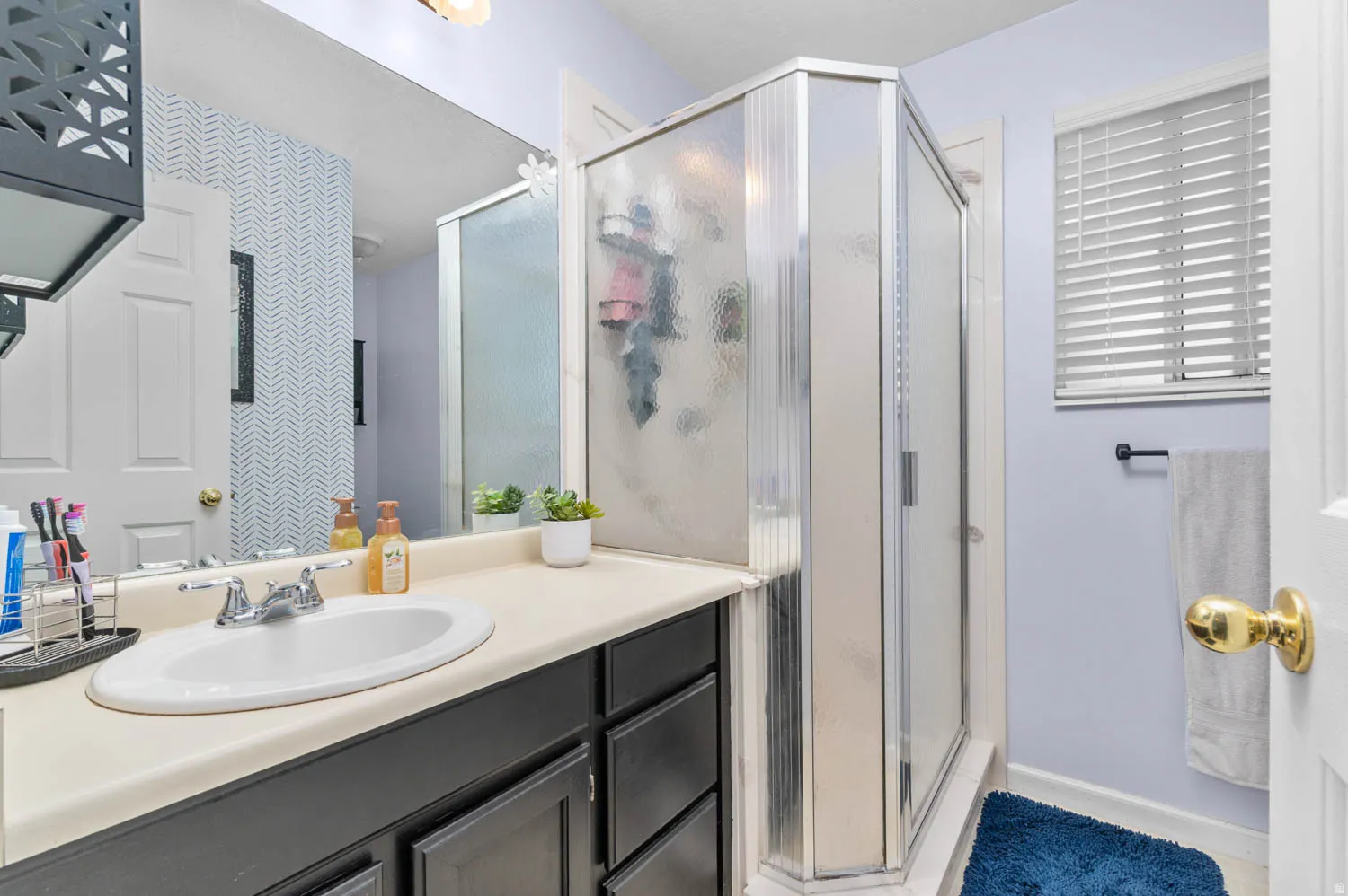 Bathroom featuring an integrated vanity sink with chrome faucet, dark wood-finish cabinetry, and a framed glass shower enclosure