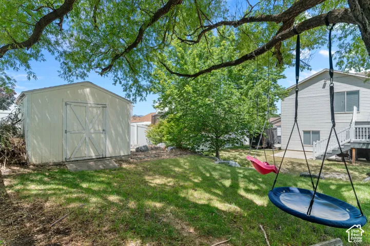 Expansive backyard featuring a lush lawn, mature trees, and a detached storage shed with double doors