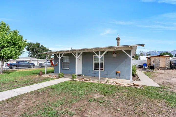 Rental: Single-story exterior featuring a covered front porch with white support columns, light blue block siding, a white front door, and a concrete walkway