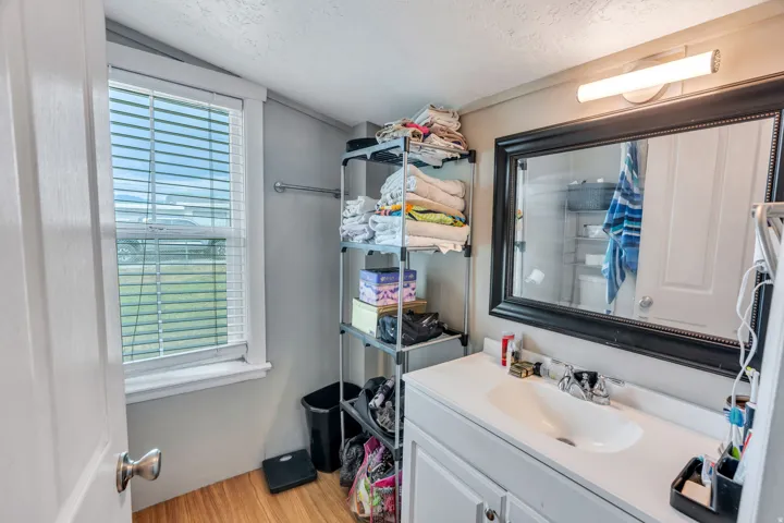 Rental: Bathroom vanity featuring a single basin sink, white cabinetry, and a large framed mirror with overhead lighting