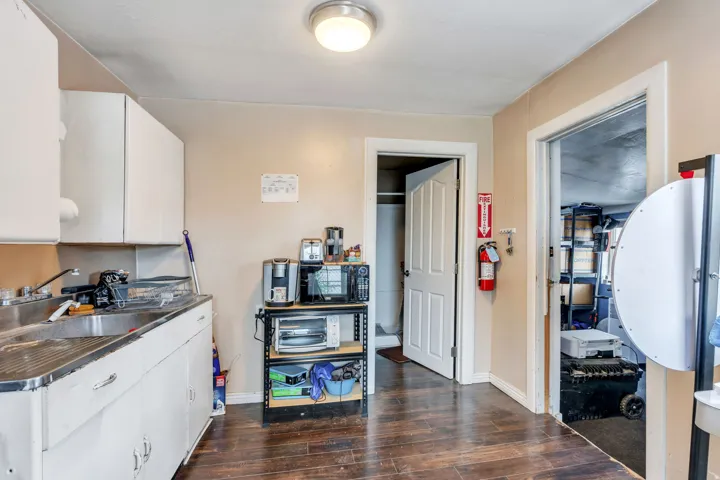 Kitchen area with white cabinetry, a double basin stainless steel sink, and wood-finish flooring
