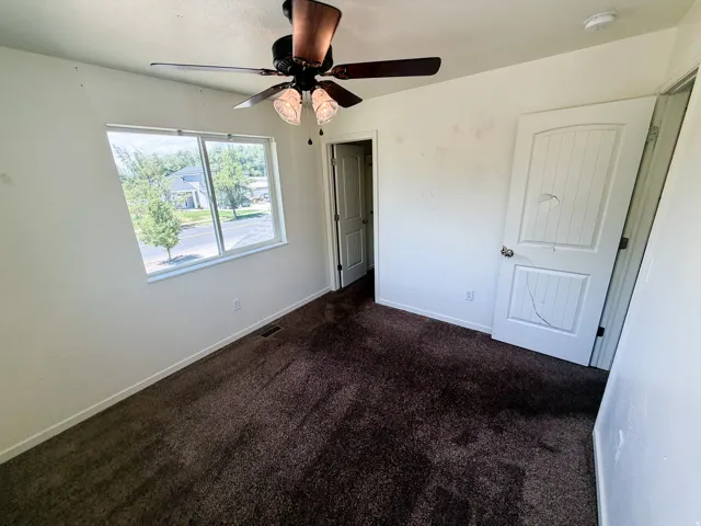 Room featuring brown carpet flooring, white walls, and a ceiling fan with integrated lighting