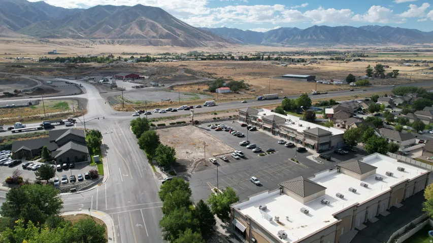 Commercial complex featuring multiple buildings with flat roofs, expansive paved parking areas, and mature landscaping