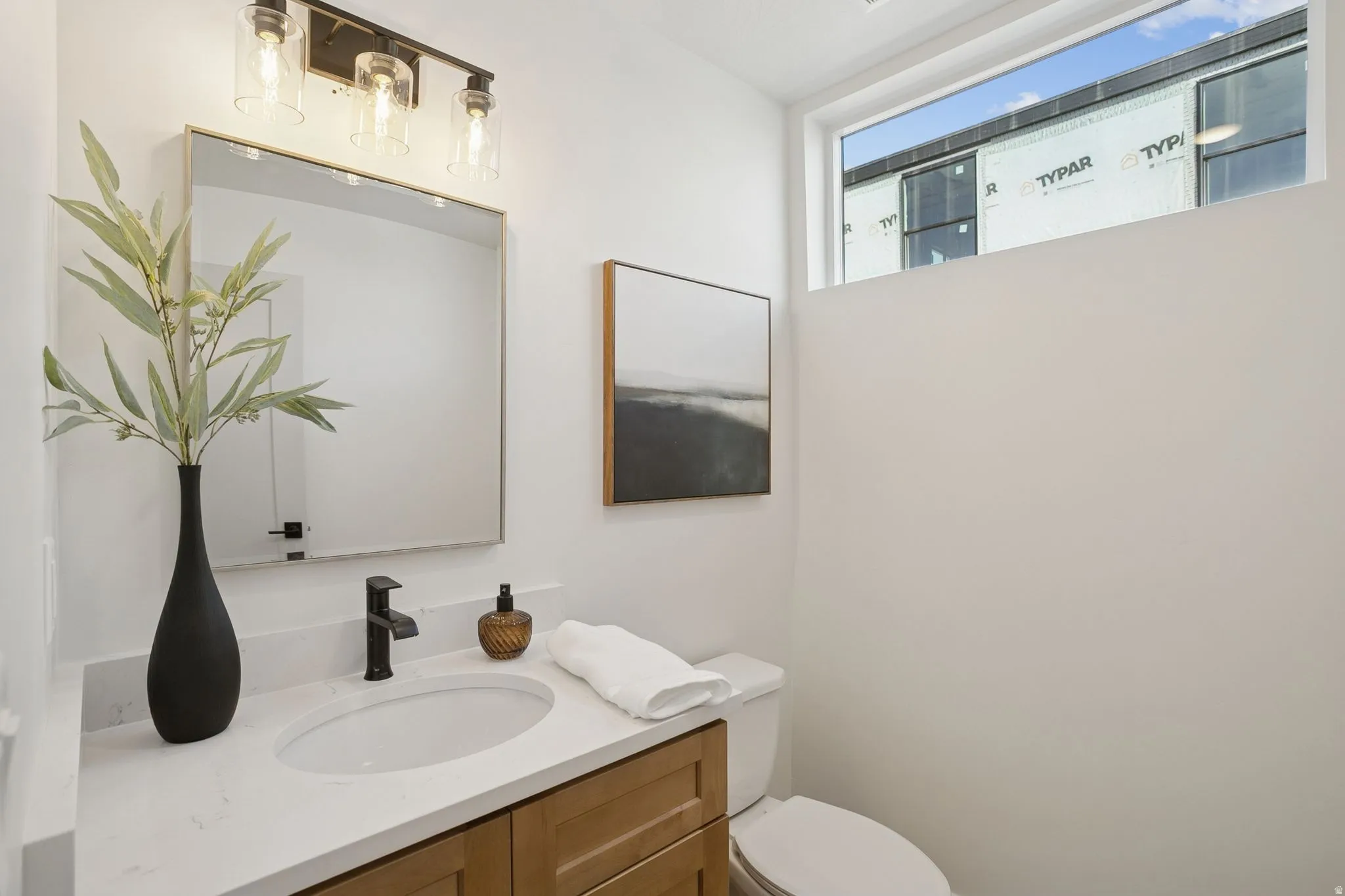 Bathroom featuring a single vanity with a white countertop, an undermount sink, a matte black faucet, and a rectangular mirror