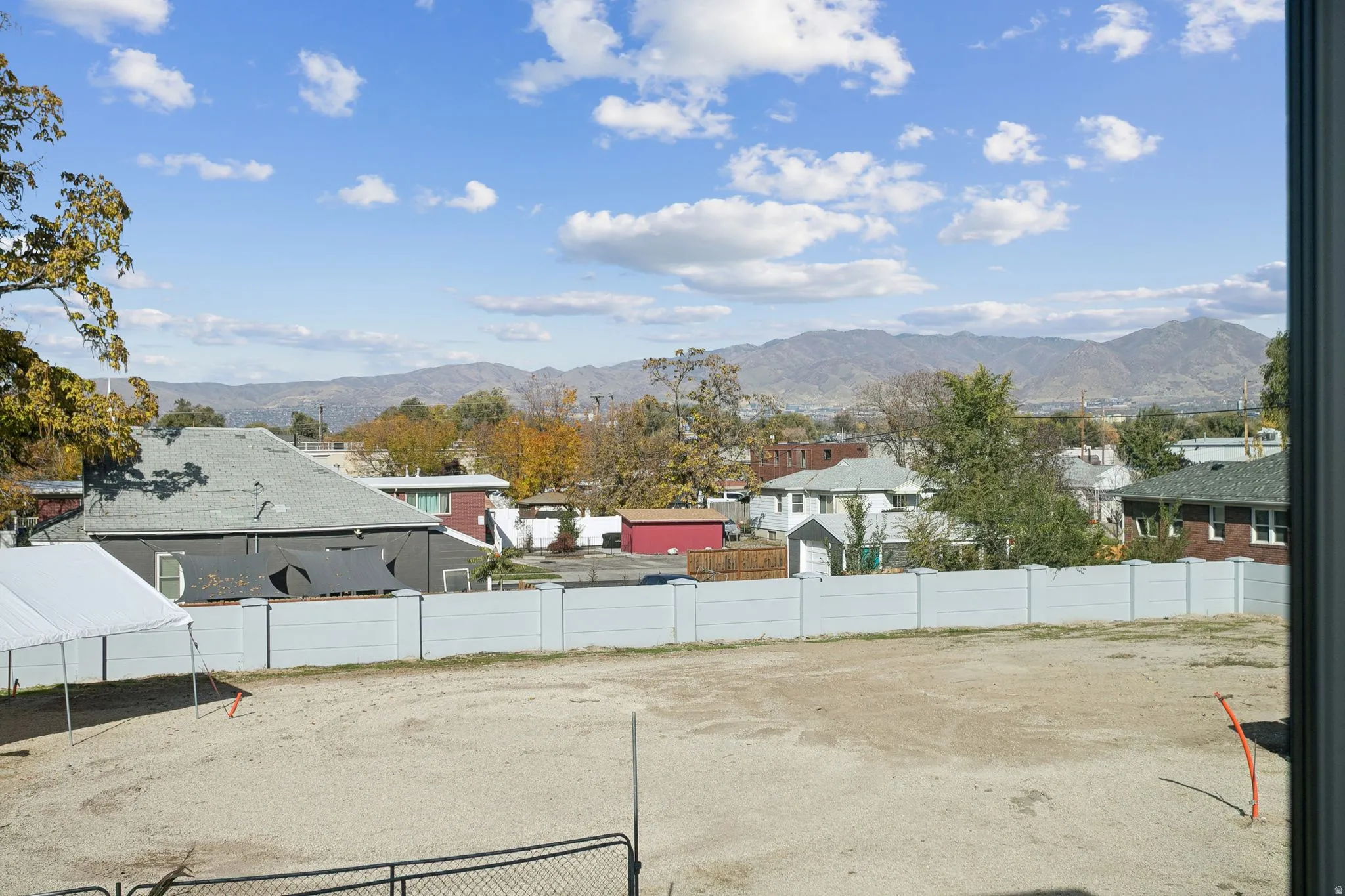 Expansive lot featuring a light-colored fence and mountain backdrop