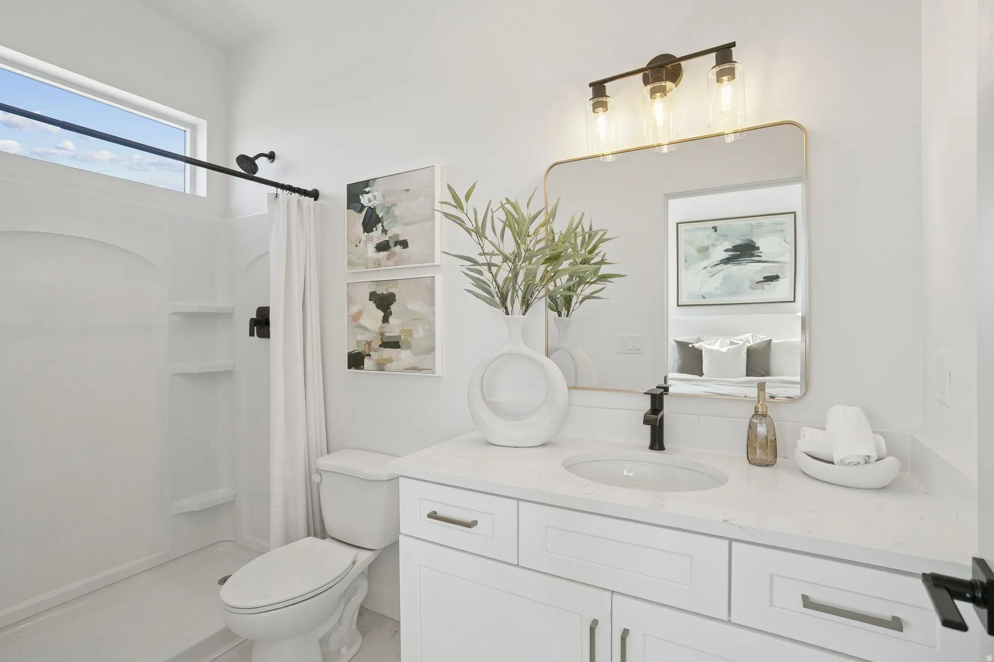 Bathroom featuring a single vanity with a white countertop and undermount sink, a framed mirror, and a three-light fixture