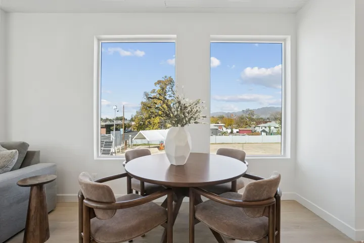 Dining area featuring two large rectangular windows, light wood-finish flooring, and white wall finishes
