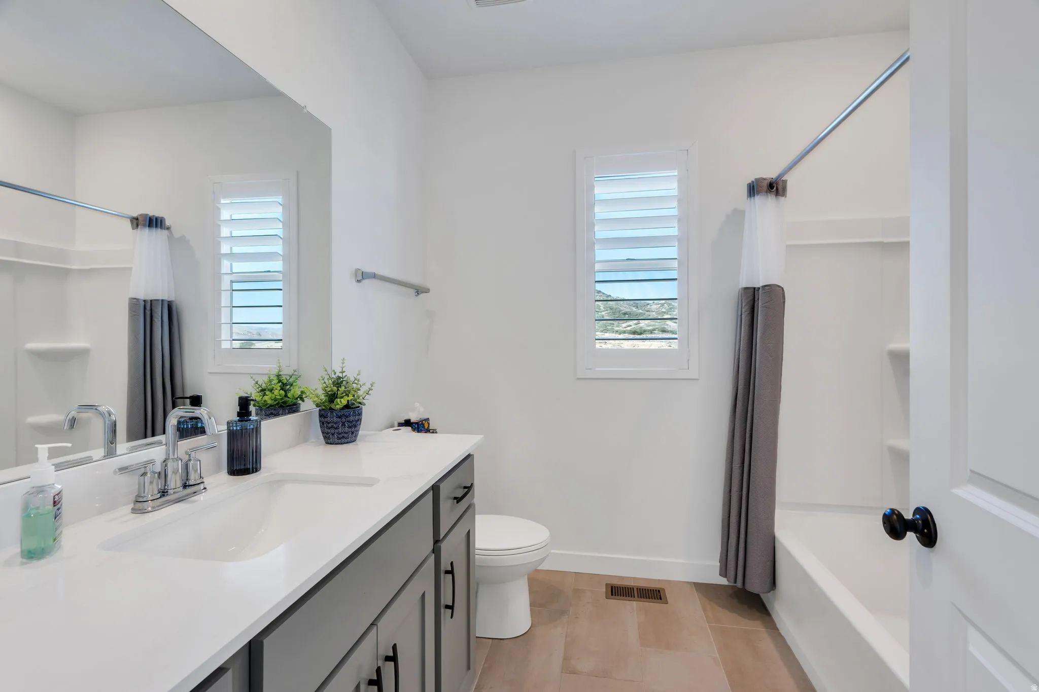Bathroom  (between 2 bedrooms) featuring a vanity with gray cabinetry, white countertop, and integrated sink