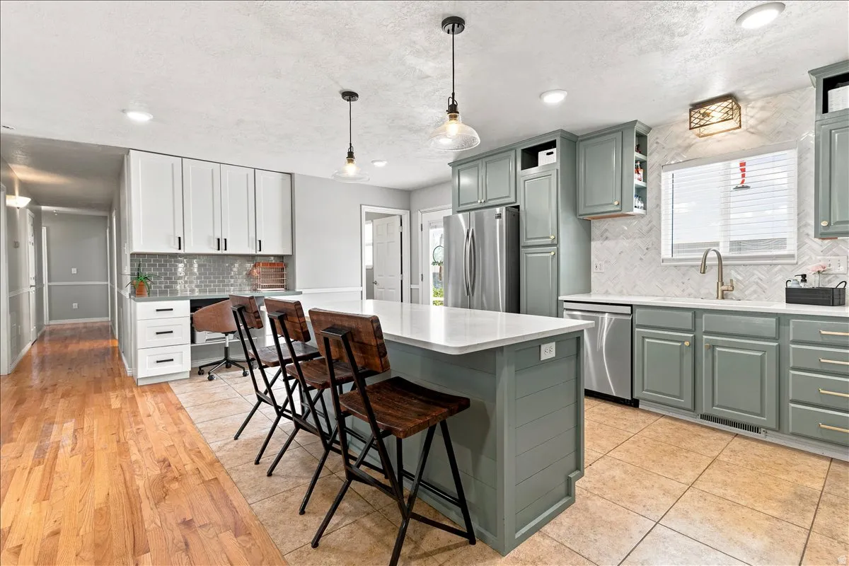Spacious kitchen featuring a central island with countertop seating, stainless steel appliances, and a tile backsplash