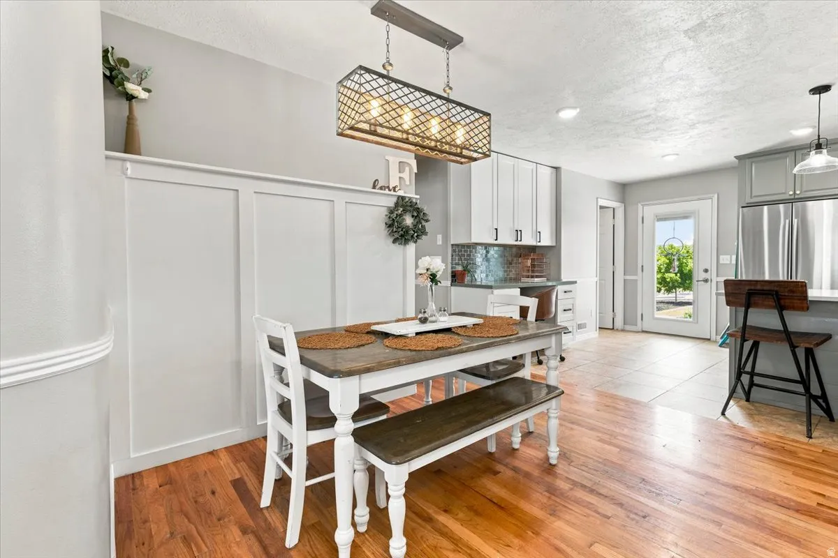 Dining area featuring wood-finish flooring, wainscoting, and a linear pendant light fixture