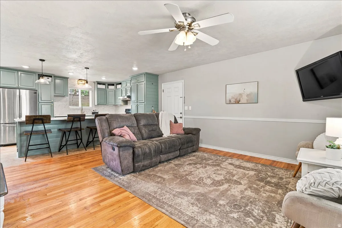 Open-concept living area featuring wood-finish flooring, a ceiling fan with integrated lighting, and a neutral color palette