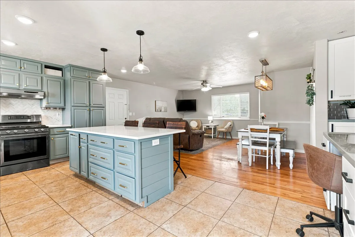Kitchen featuring a center island with extensive cabinetry, blue-painted shaker-style cabinets, a stainless steel range, and a white herringbone tile backsplash