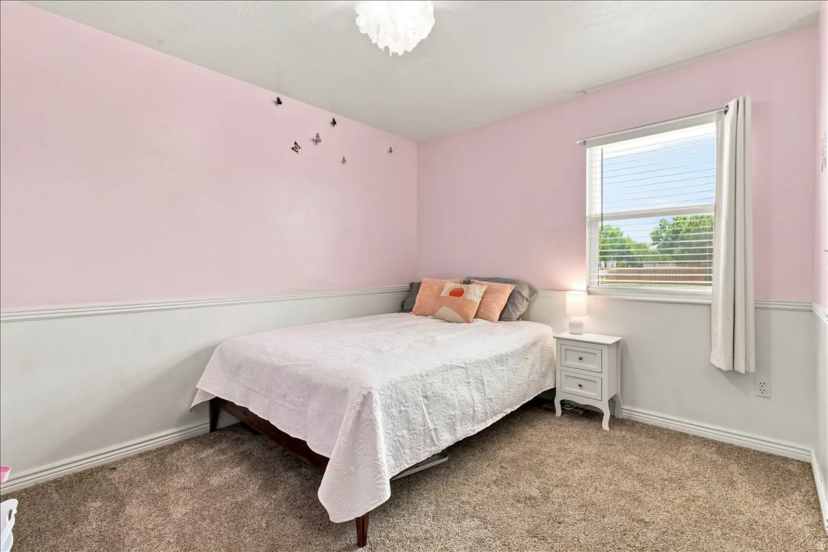 Carpeted room featuring a single window with horizontal blinds, a ceiling-mounted light fixture, and two-tone walls with wainscoting