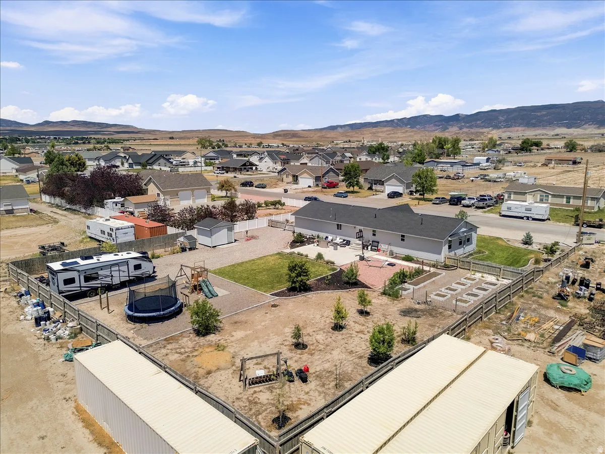 Expansive property featuring a fenced perimeter, a large paved patio, and multiple garden beds