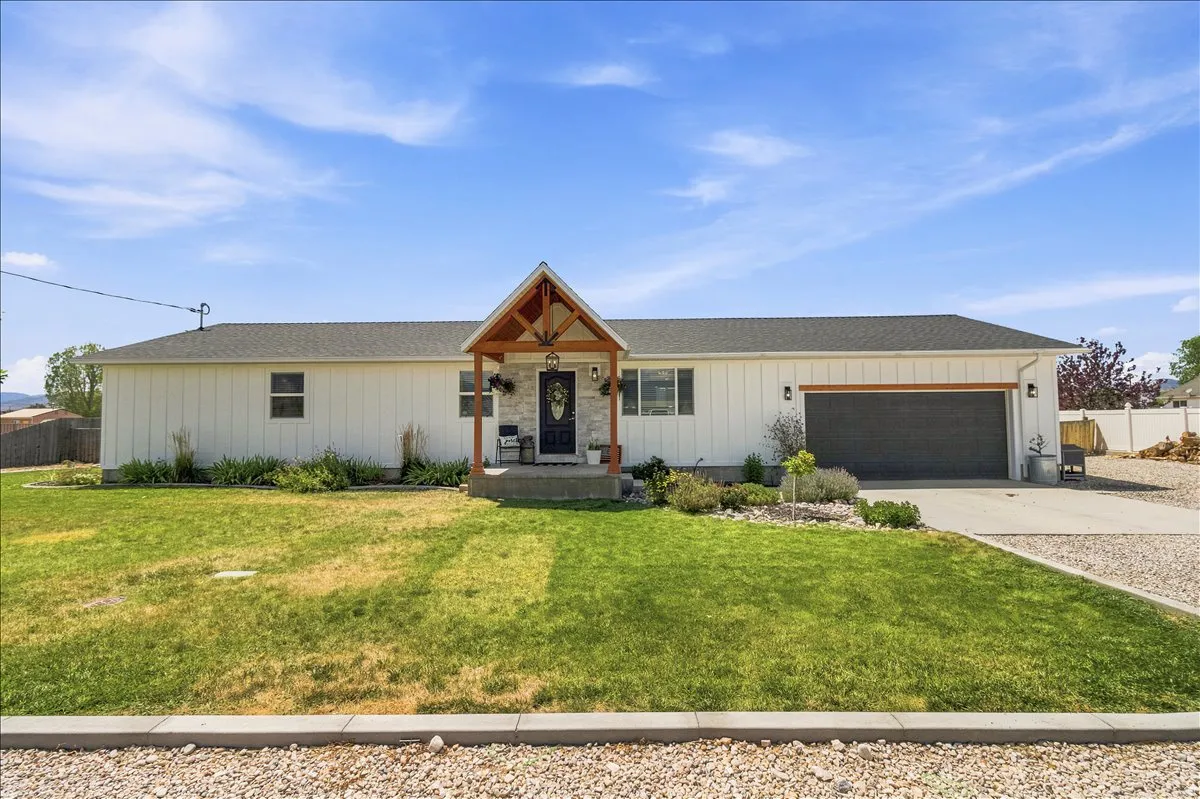 Single-story residence featuring white board and batten siding, a dark asphalt shingle roof, and a prominent covered entry with wood-beam accents