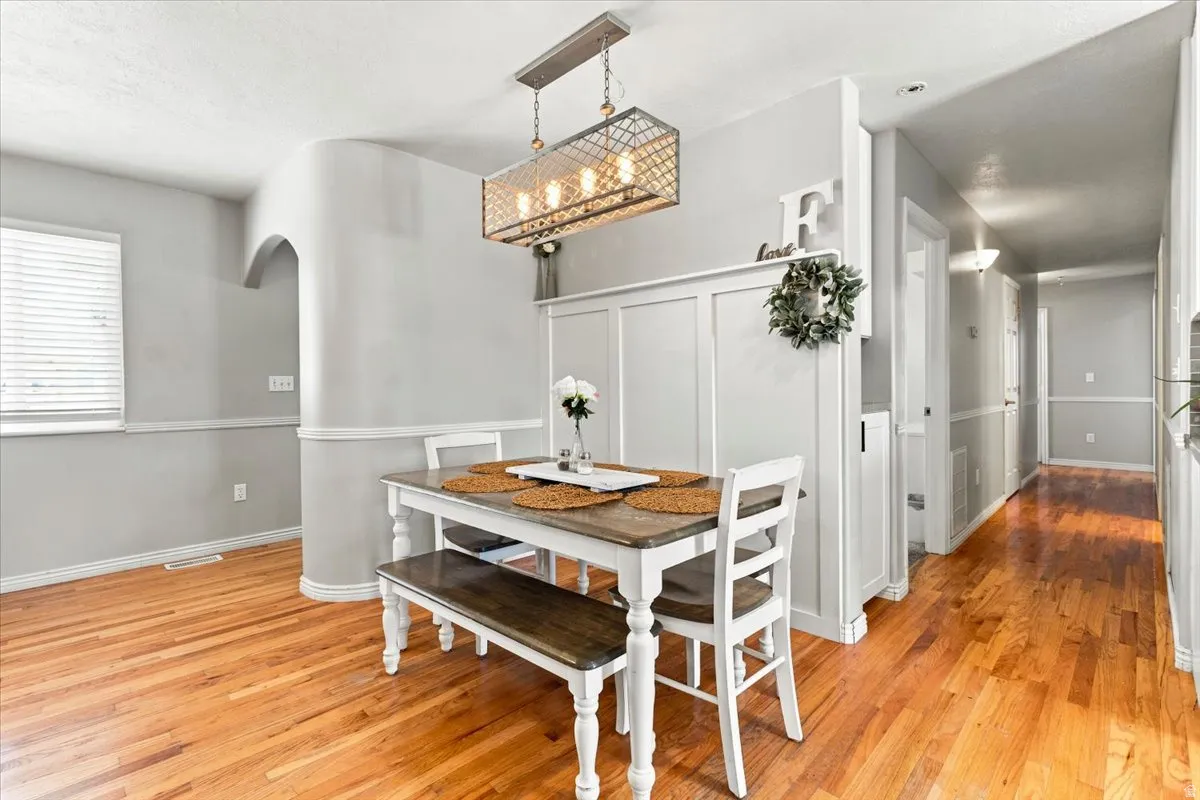 Hardwood flooring throughout, featuring a modern chandelier, white trim, and wainscoting