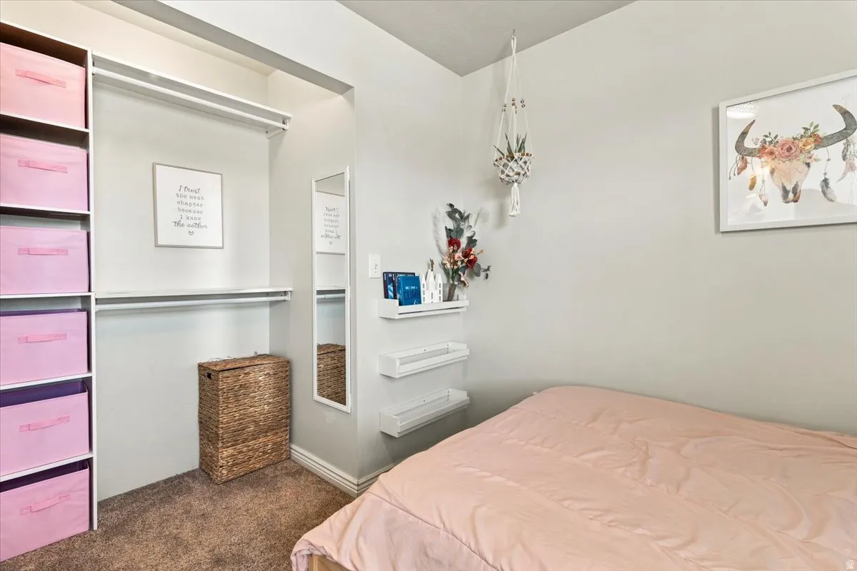 Bedroom featuring a built-in closet system with shelving and hanging rods, a wall-mounted full-length mirror, and light gray wall paint