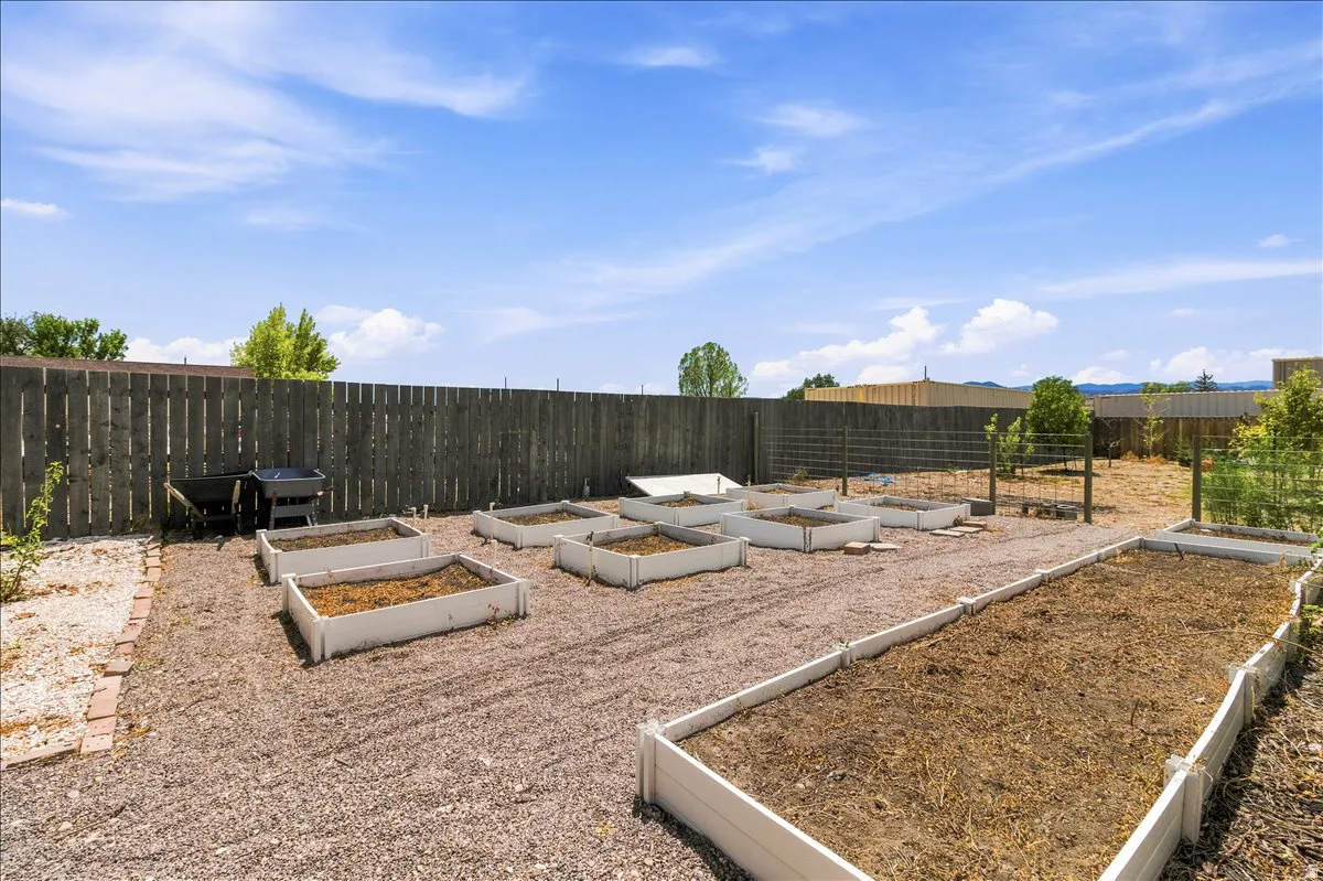Outdoor garden area featuring multiple raised beds, a full privacy fence, and a gravel ground cover