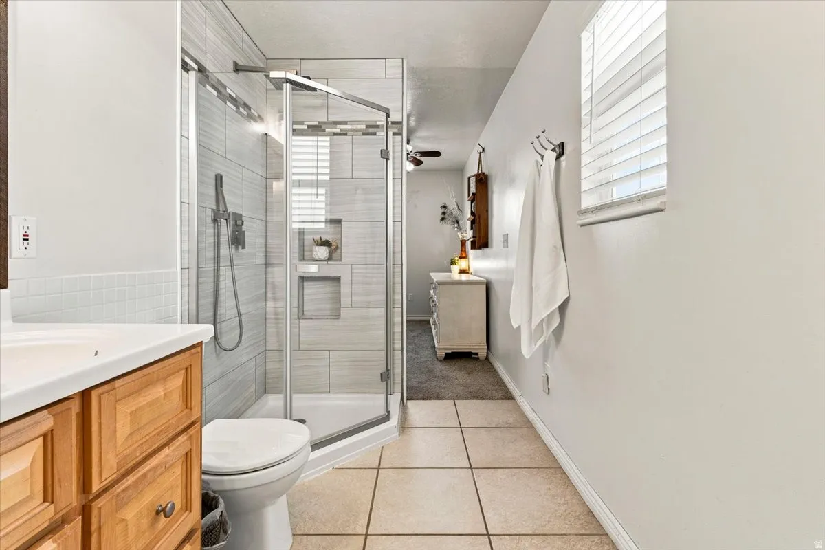 Tiled shower with glass enclosure and built-in niches, accompanied by a wood-finish vanity with an integrated sink