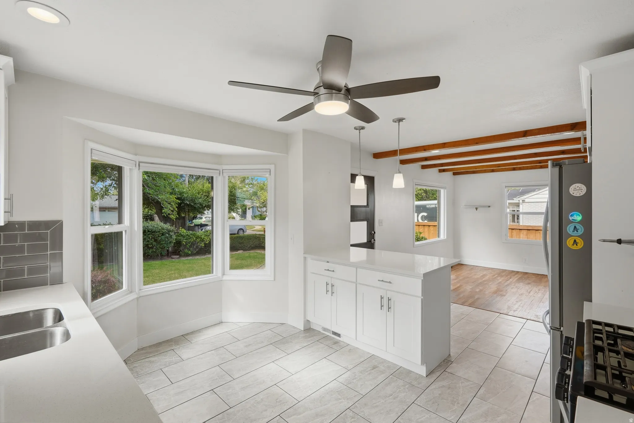 Kitchen featuring a bay window, white cabinetry, a central island with a solid surface countertop, stainless steel appliances, and tile flooring