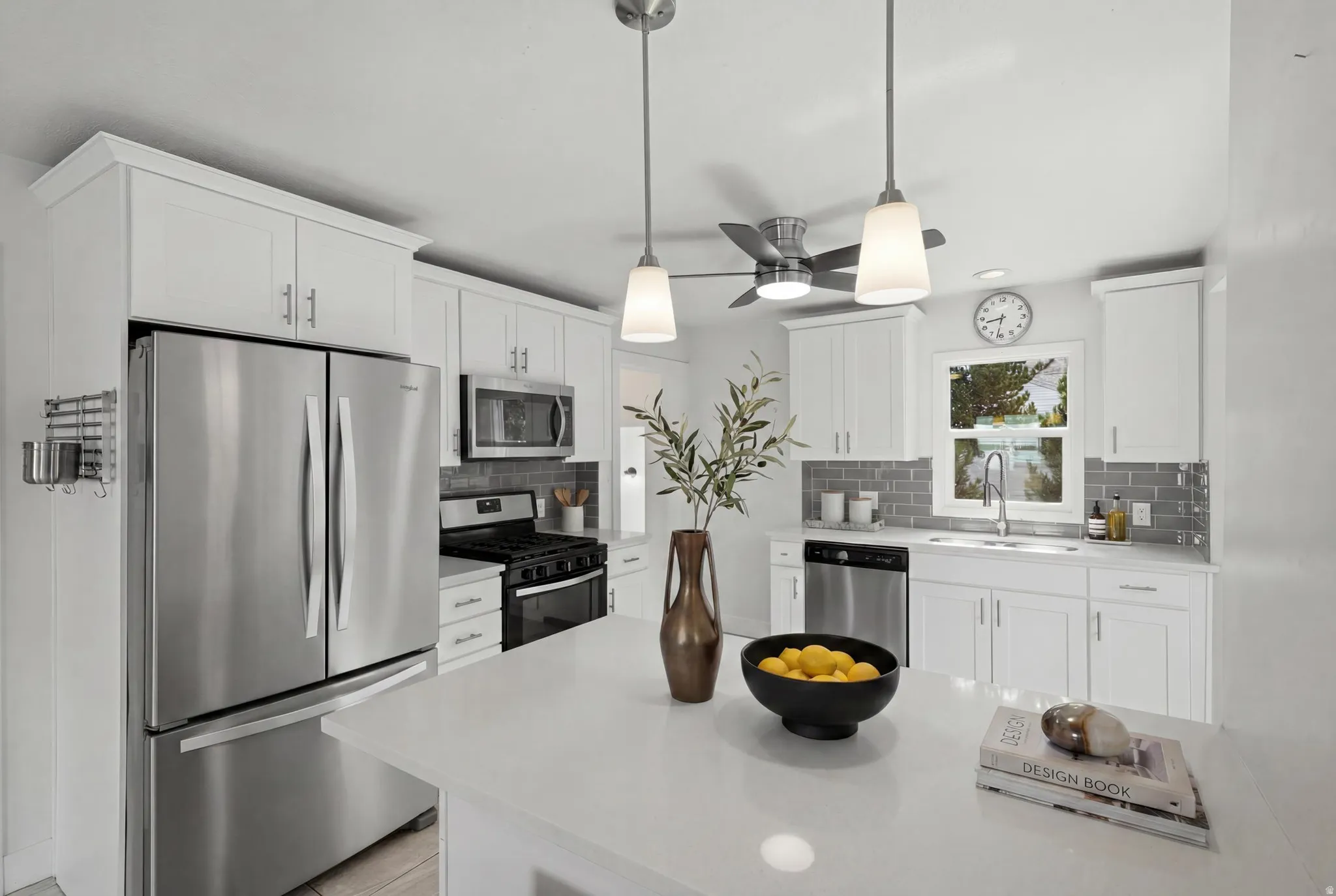 Virtually staged. Modern kitchen featuring a central island, stainless steel appliances, white cabinetry, a subway tile backsplash, and recessed lighting