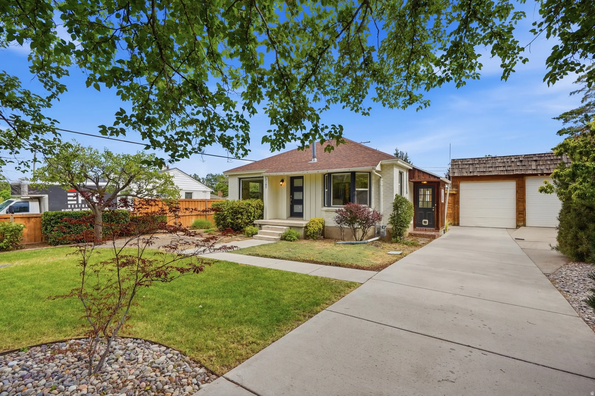 Exterior featuring a manicured lawn, established landscaping, and a multi-car driveway