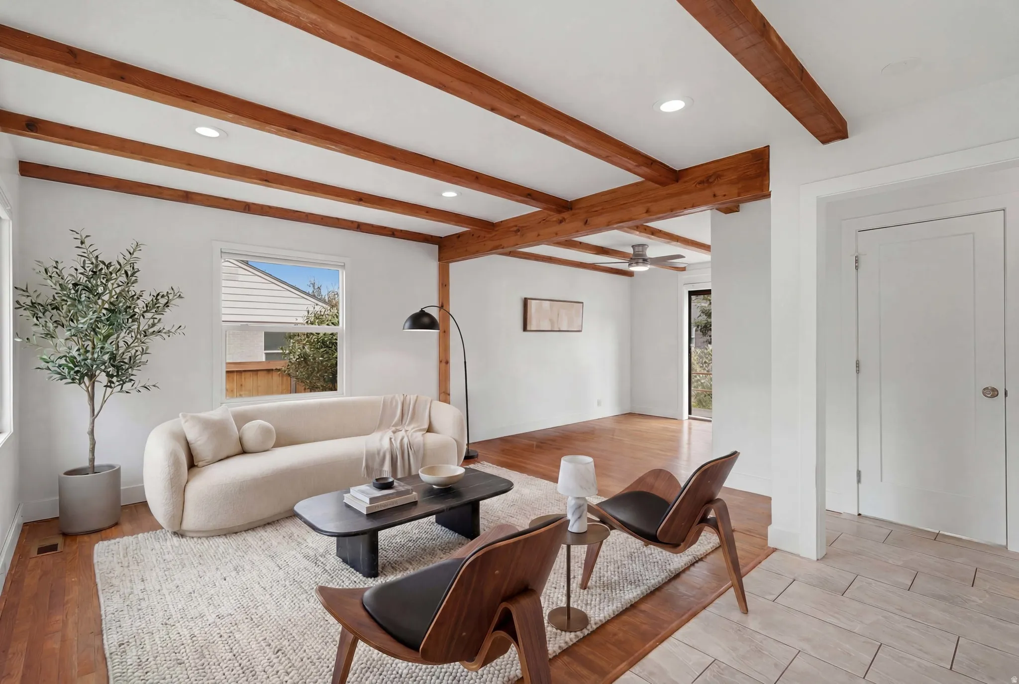 virtually staged. Exposed wood beam ceiling in a living area featuring wood-finish flooring and recessed lighting