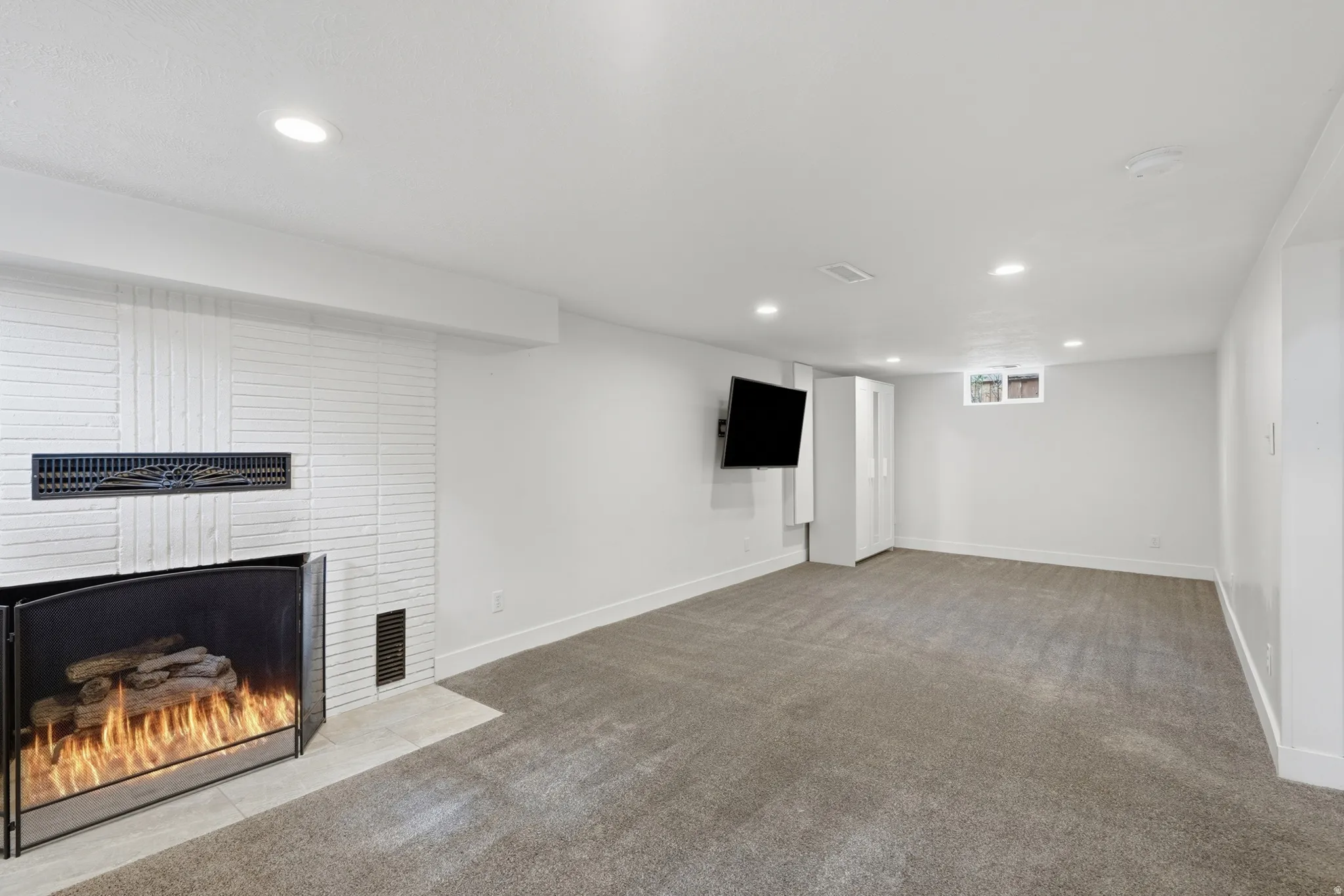 White brick fireplace with a black screen and log insert